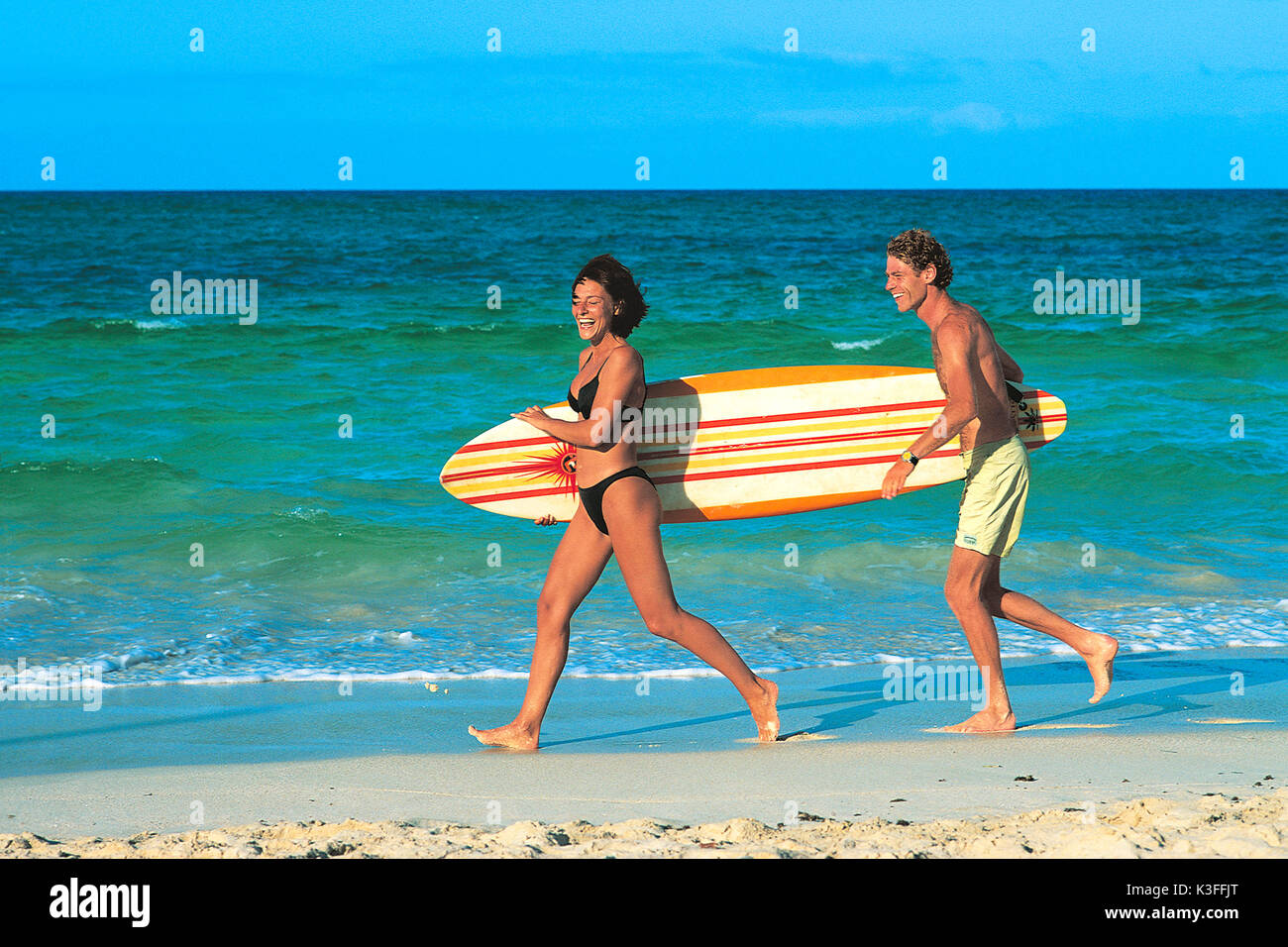 El hombre y la mujer con tablas de surf en el mar Foto de stock