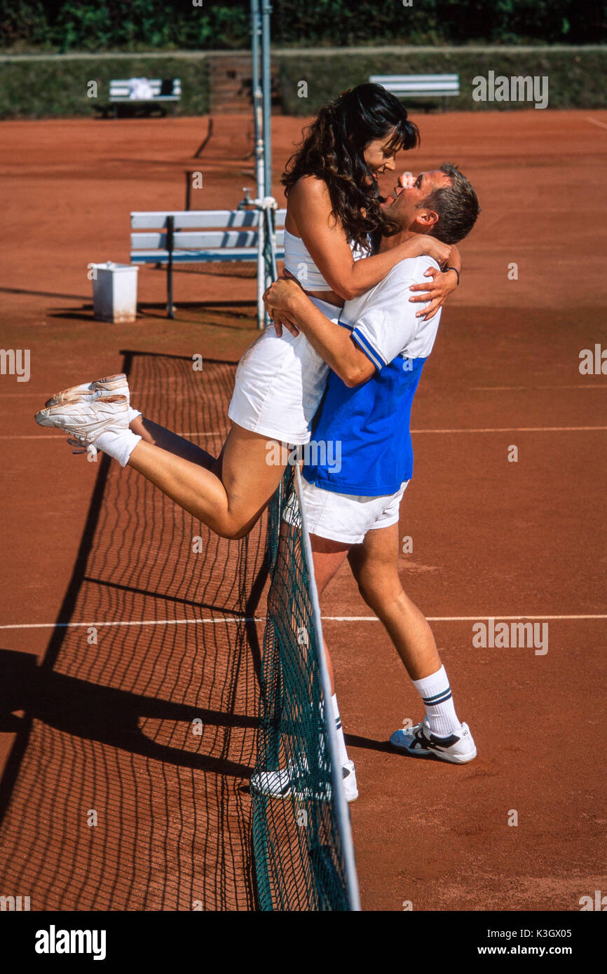Pareja en el tenis abraza en la red Foto de stock