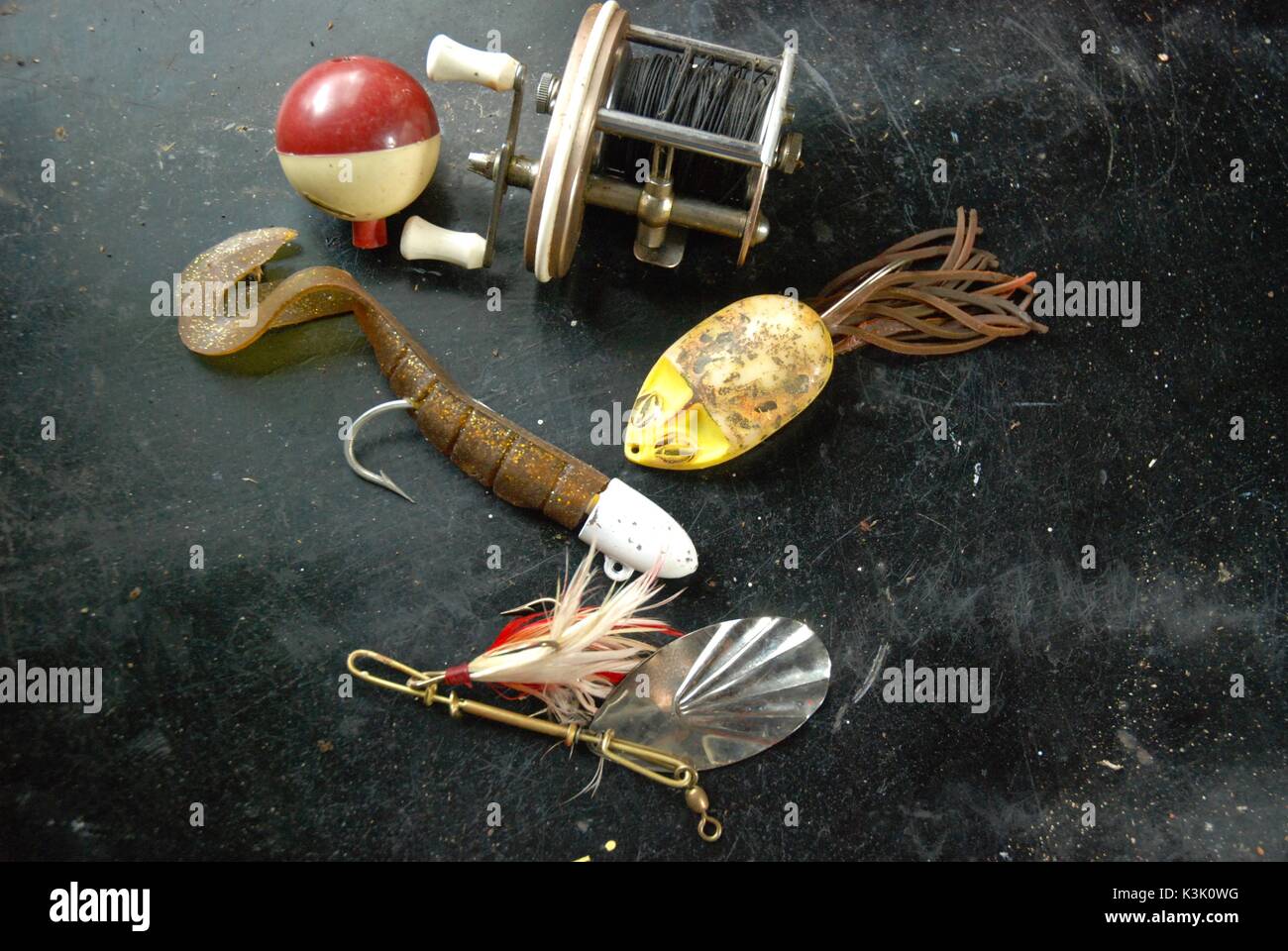 Vintage colección de señuelos de pesca, corcho y carrete de pesca sobre la  superficie de trabajo negra Fotografía de stock - Alamy