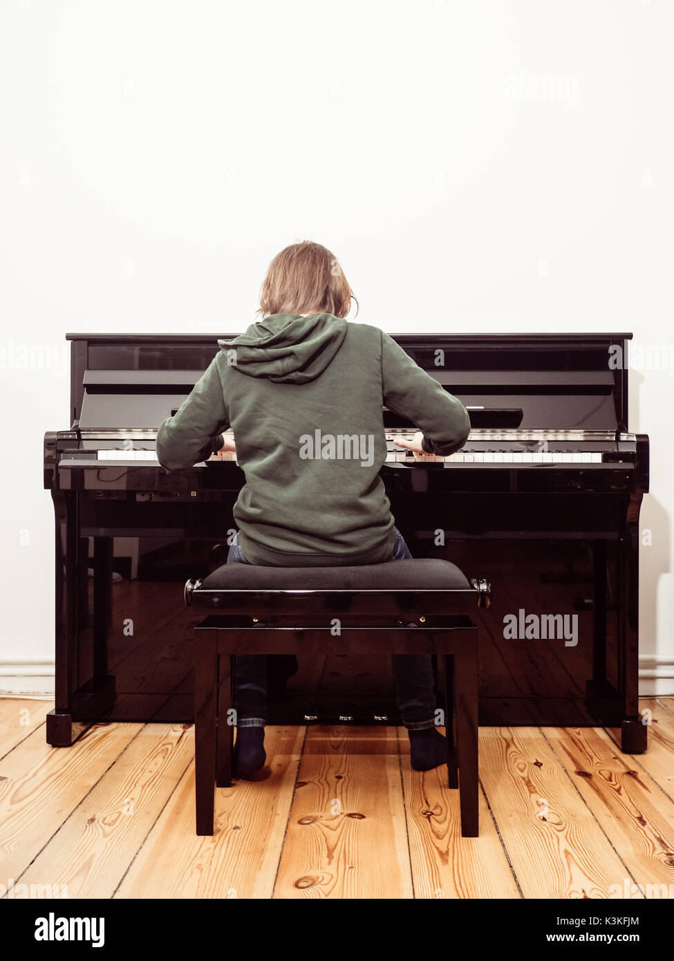 Vista trasera de un niño que jugaba en un piano digital negro Foto de stock