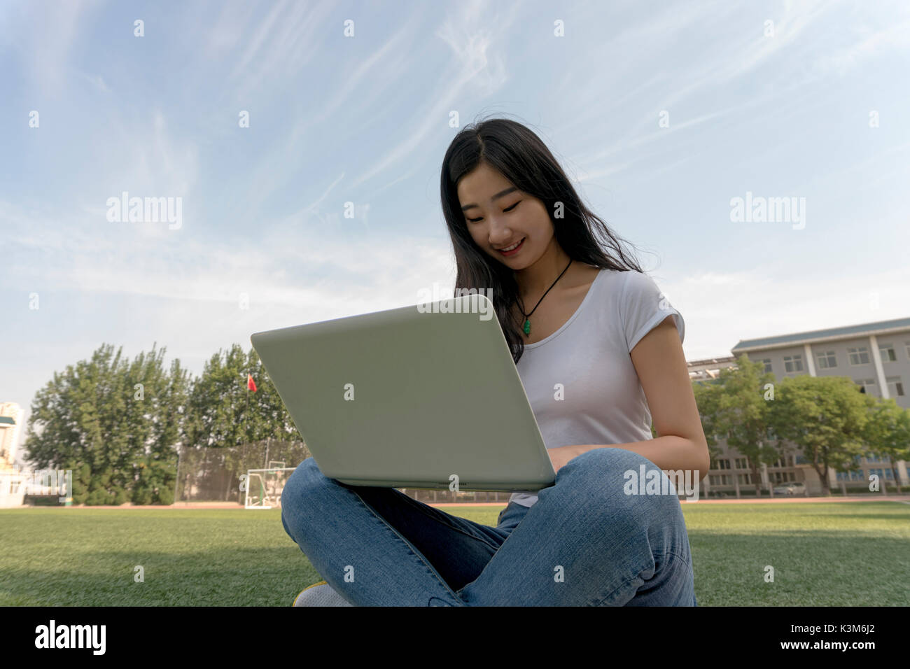 Bella asiática estudiante universitario con laptop ,sentado en el patio de recreo. Foto de stock