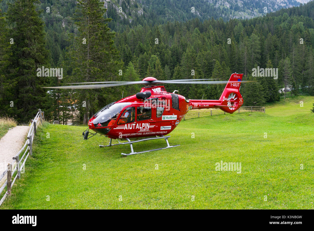 Rescate rojo elicopter aterrizó en una pradera, Funes valle, dolomitas, Sudtirol, Italia Foto de stock