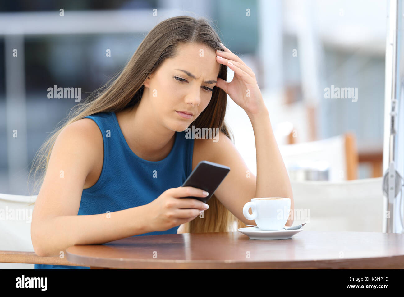 Preocupado única mujer viendo un teléfono móvil y esperando una llamada o mensaje sentado en una cafetería Foto de stock