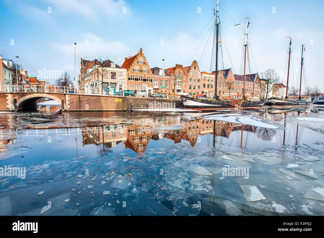 Edificios en Harleem reflejando en la mitad del río Spaarne congelado