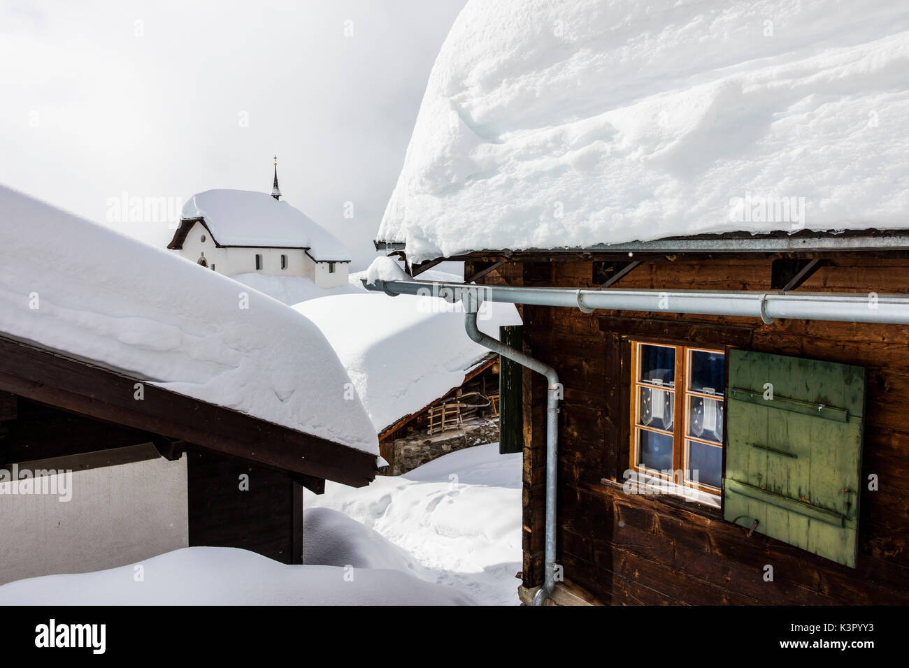 La iglesia alpina rodeada por cabañas de montaña inmersos en la nieve Bettmeralp Raron distrito del cantón de Valais Suiza Europa Foto de stock