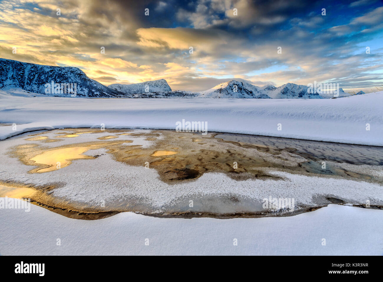 El amanecer dorado se refleja en una piscina de aguas cristalinas donde la nieve es casi derretido. Las Islas Lofoten Noruega Europa Haukland Foto de stock