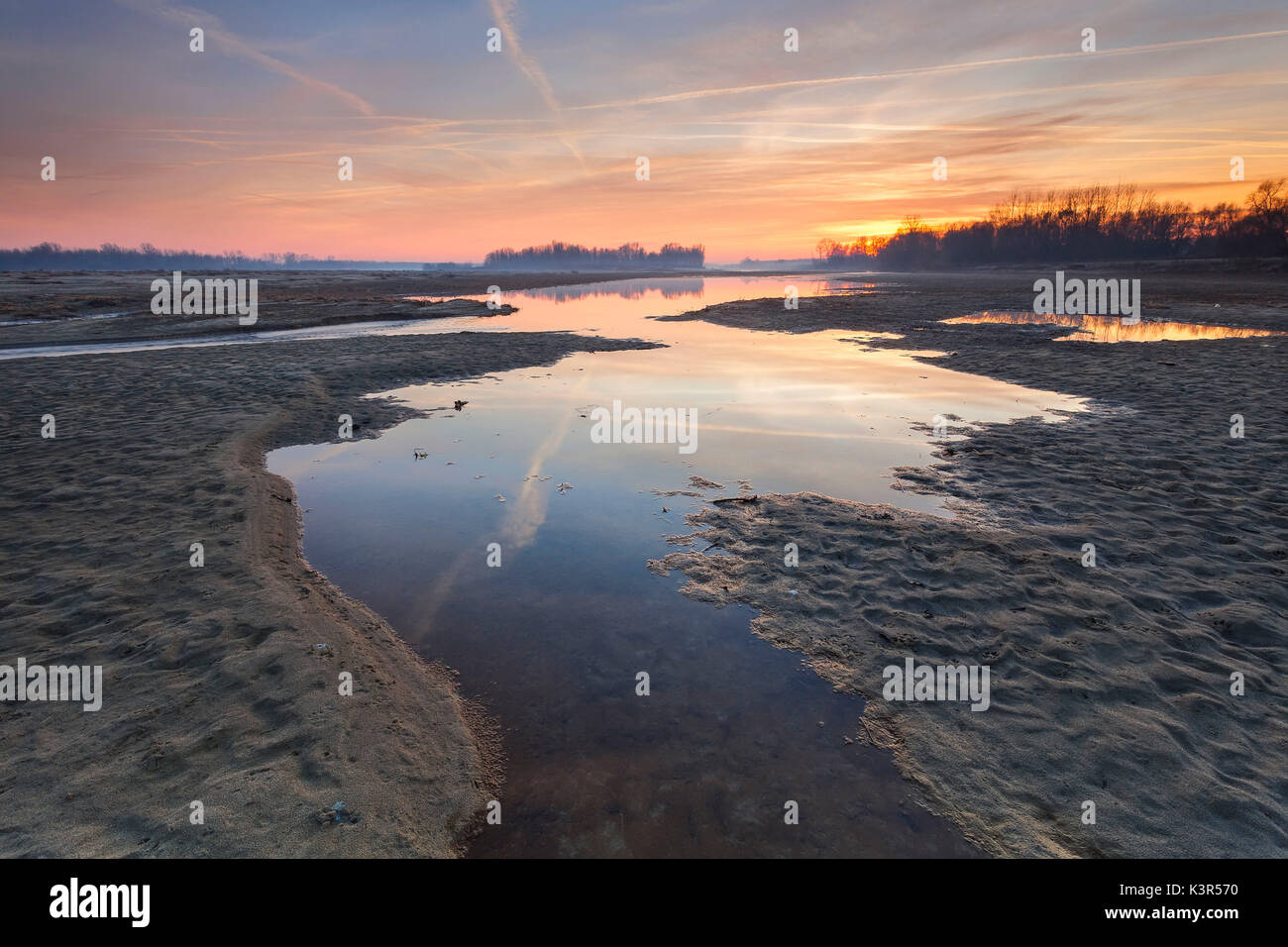 Parque del río Po, Italia. Los arroyos en la arena con el reflejo de una puesta de sol de invierno de color Foto de stock
