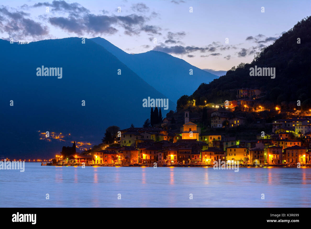 Peschiera Maraglio poco después de la puesta del sol, las luces de la pequeña aldea de Montisola, la isla lacustre más grande de Europa, en la provincia de Brescia, el lago de Iseo Foto de stock