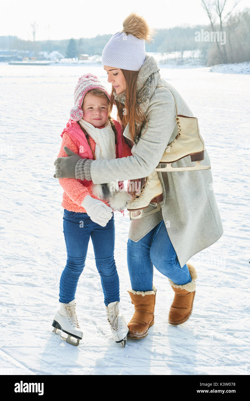 Hija de madre consuela al patinaje sobre hielo en invierno Foto de stock