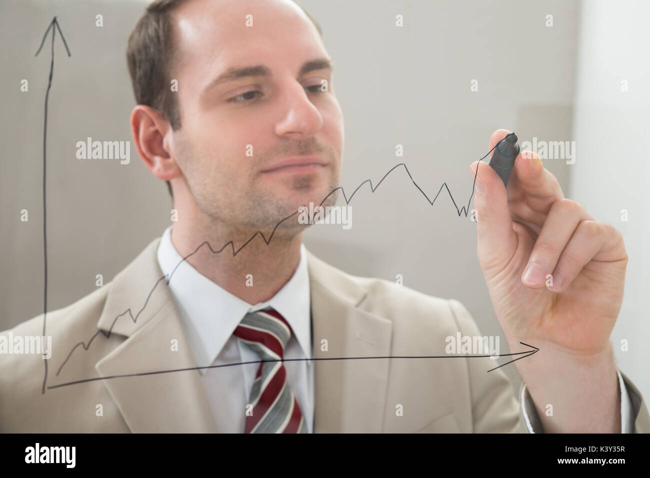 Empresario de dibujar un gráfico en un panel de vidrio con rotulador Foto de stock