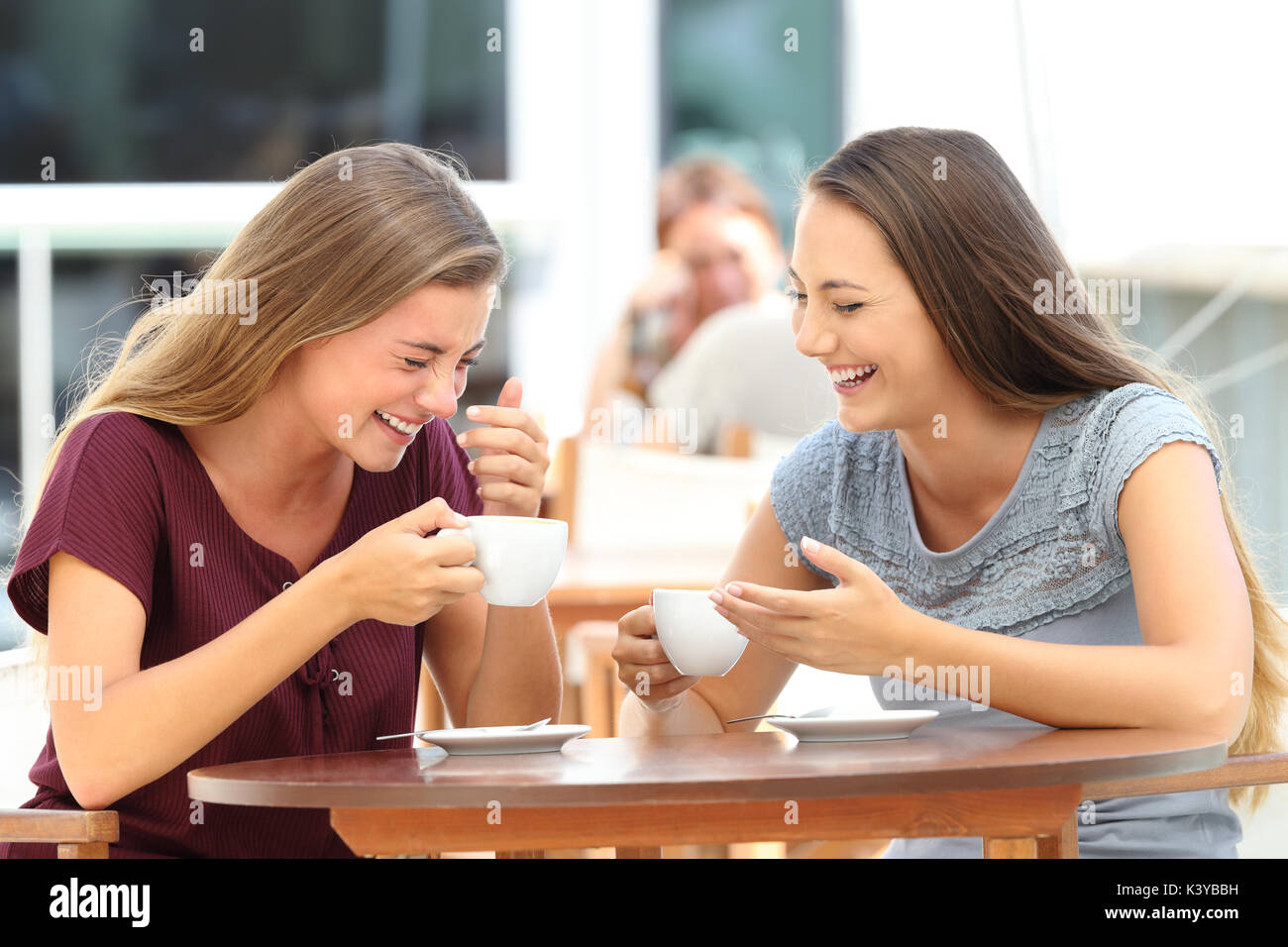 Dos mejores amigos riendo ruidoso durante una conversación sentado en un restaurante Foto de stock