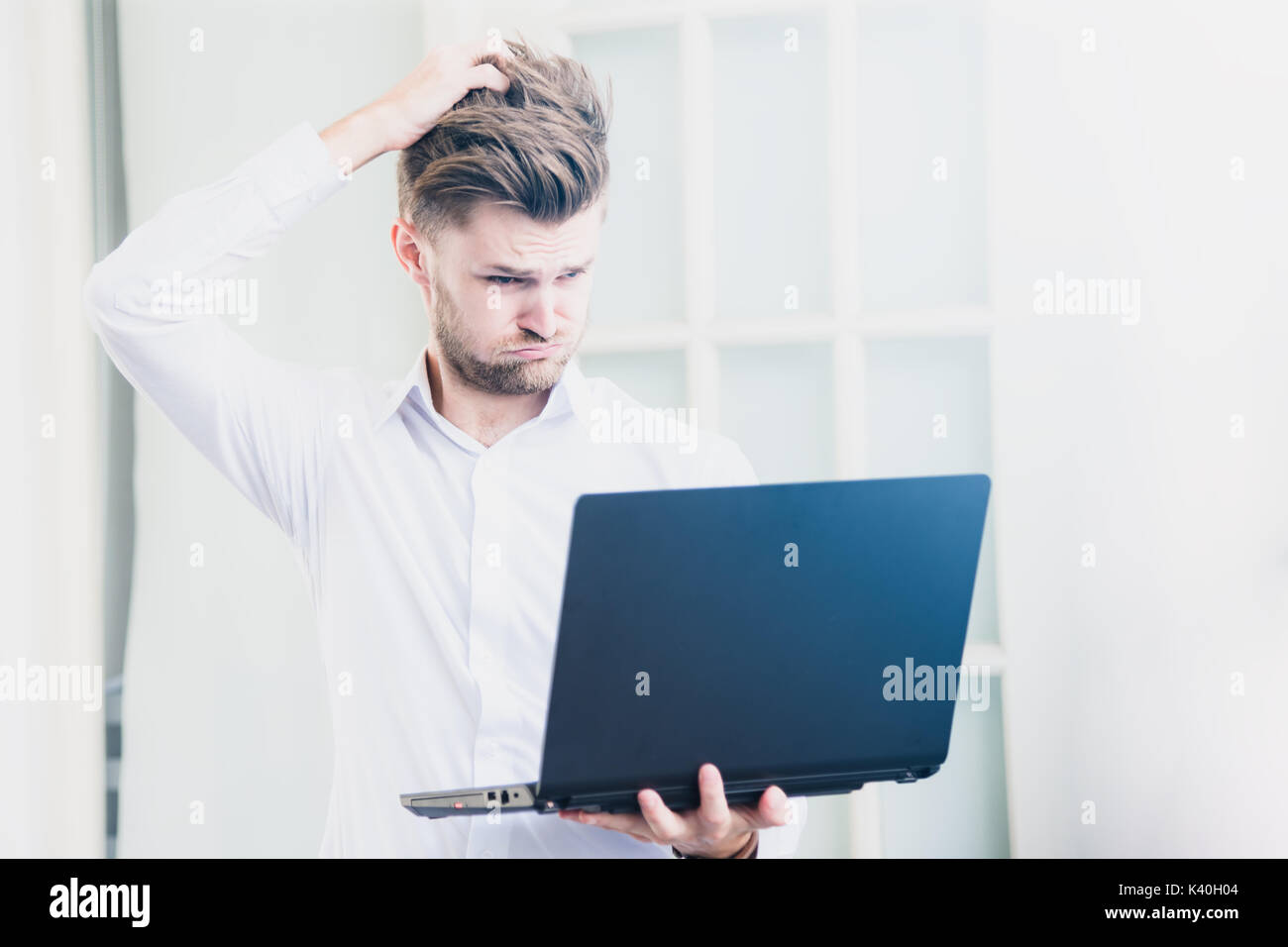 Joven empresario busca portátil con conmocionó el estrés negativo, la postura en la oficina Foto de stock