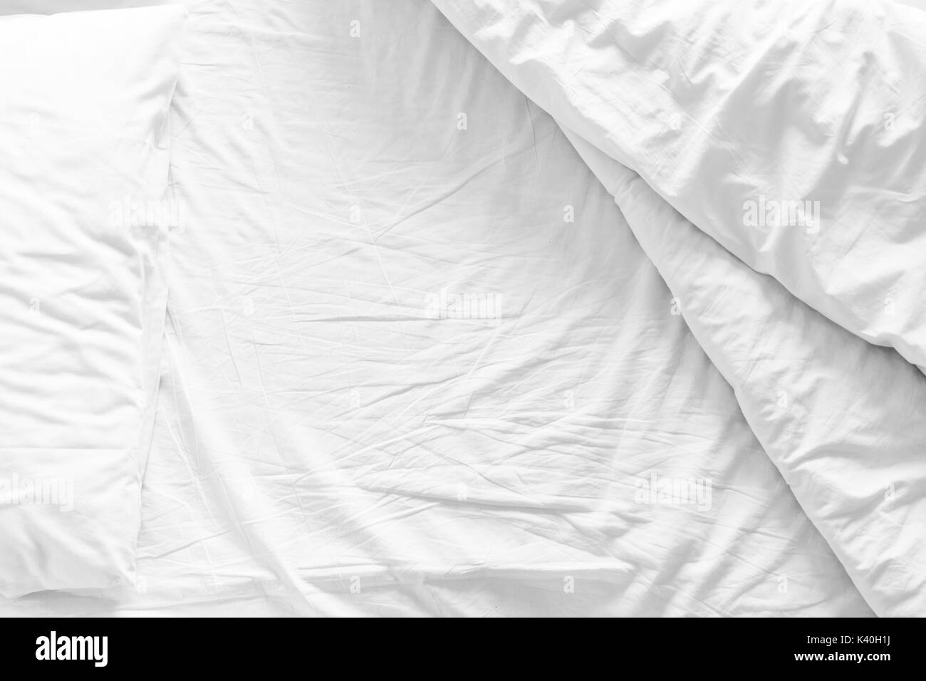 Deshacen la cama con sábana arrugado, una manta y almohadas Confort edredón dormir después de despertarse en la mañana. Foto de stock