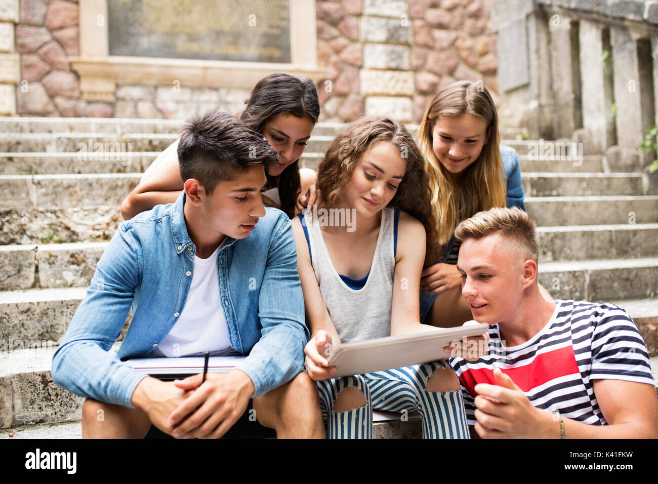 Los estudiantes adolescentes con tablet sentado en escalones de piedra. Foto de stock