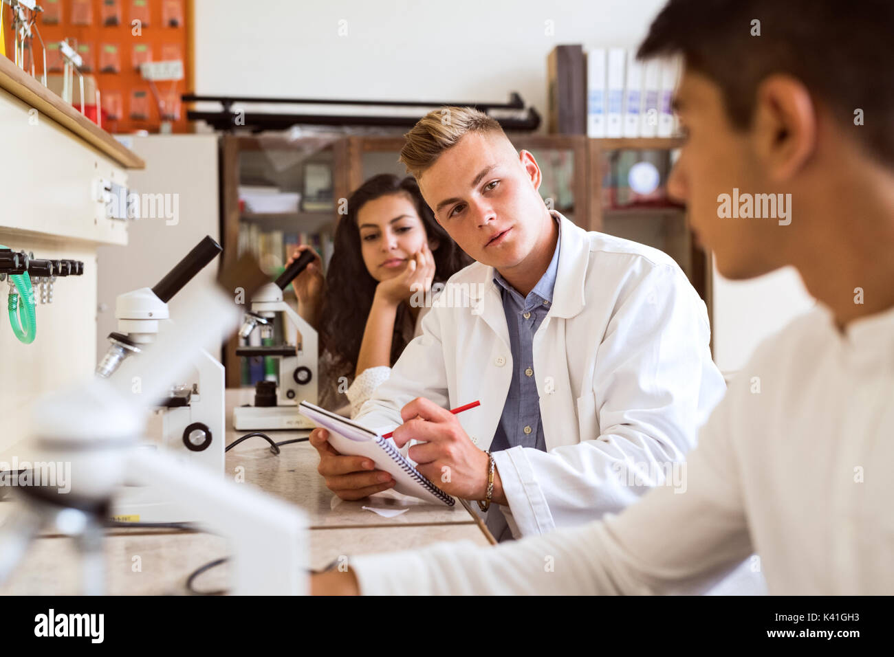 Estudiante de la High School secundaria con microscopios en laboratorio. Foto de stock