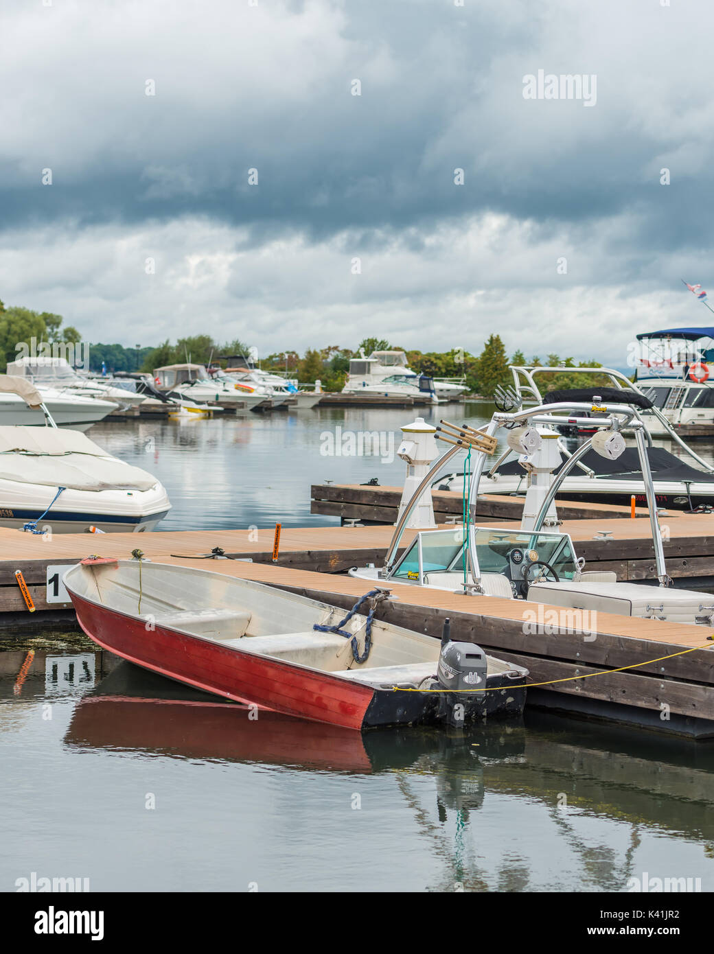 Roja pequeña lancha fuera borda está acoplado entre grandes barcos más caros en Orillia Ontario mostrando que el paseo en bote puede ser disfrutado por todos. Foto de stock