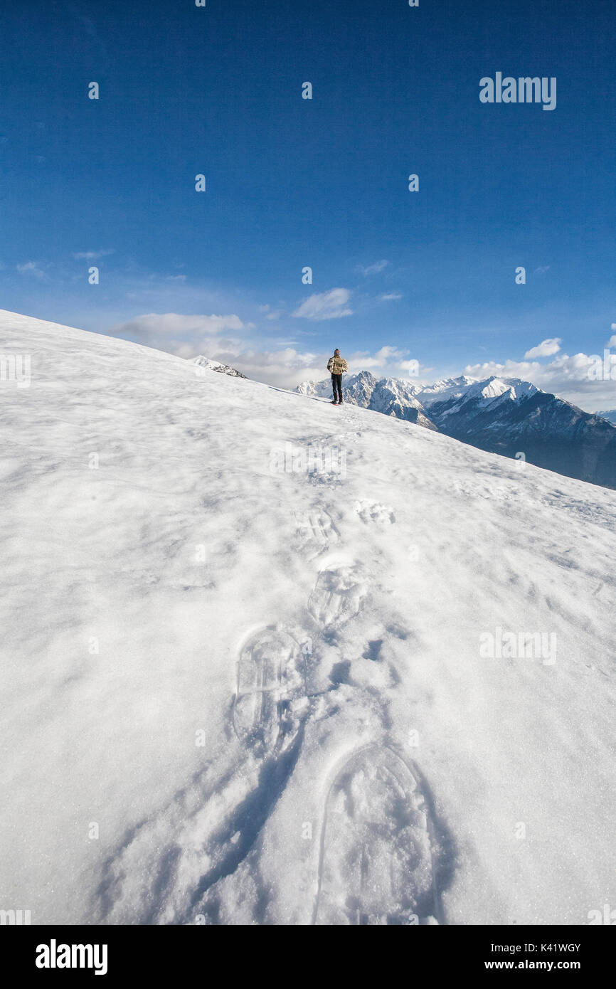 Caminante admira los picos nevados de las montañas Vercana Masino grupo alto Lario Lombardía Italia Europa Foto de stock