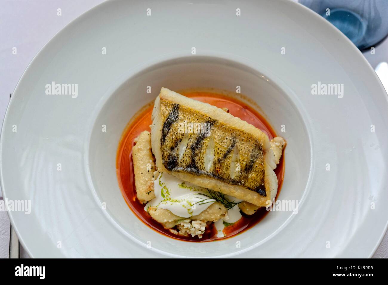 Restaurantes de calidad, sopa de pescado con queso de la cabaña, fideos enelados y perca de picio frito en sopa de pescado Foto de stock