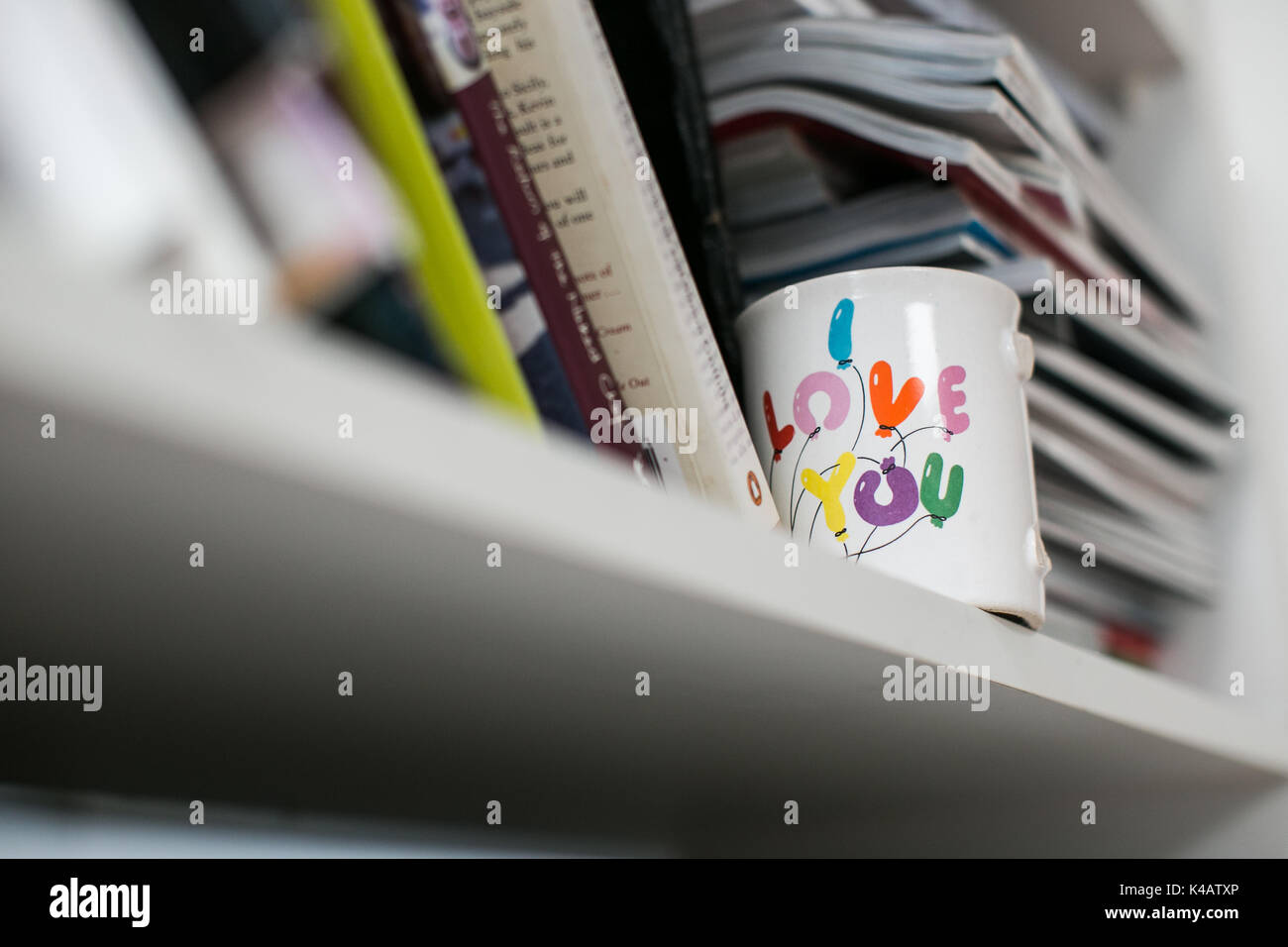 Una taza con un asa rota y mensaje sentimental en un estante en una casa de familia Foto de stock