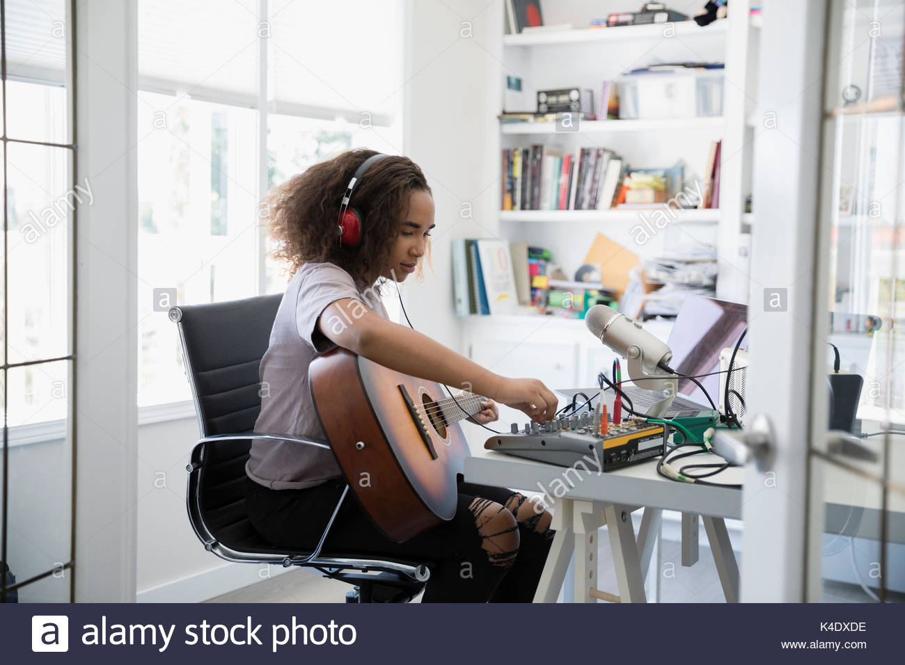 Adolescente tocando la guitarra, la grabación de música en micrófono y equipos de oficina en casa Foto de stock