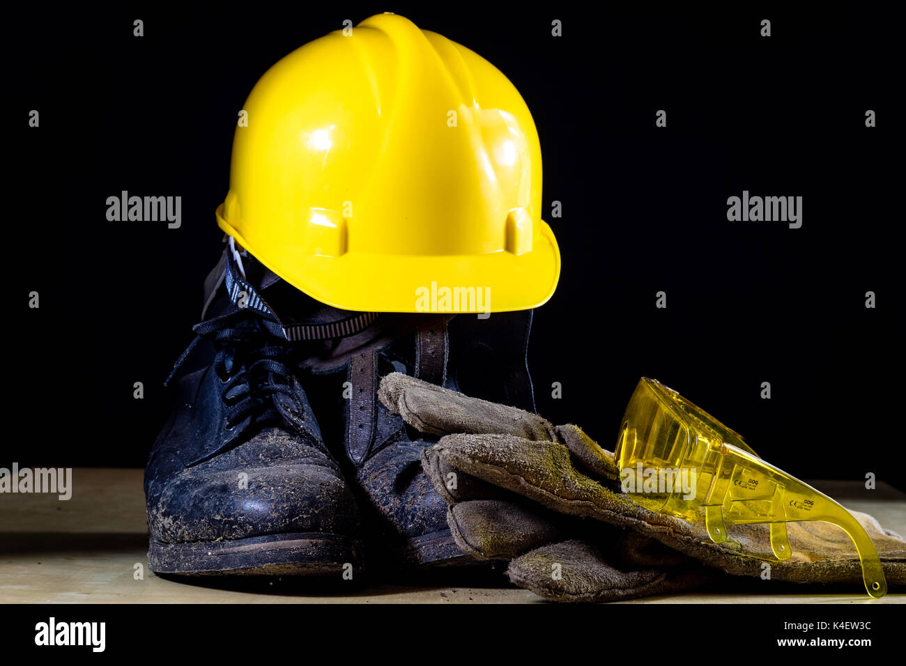 Ropa de trabajo para un trabajador de la construcción. casco, guantes,  calzado y gafas de sol en una mesa de madera. fondo negro Fotografía de  stock - Alamy