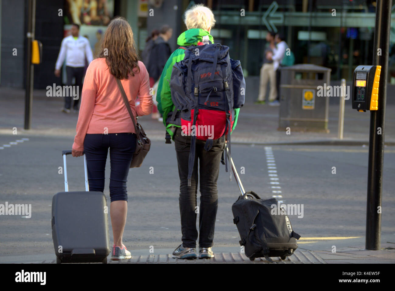 Glasgow street scene turistas americanos cruzando sapo en el semáforo con carro de casos y mochila Foto de stock