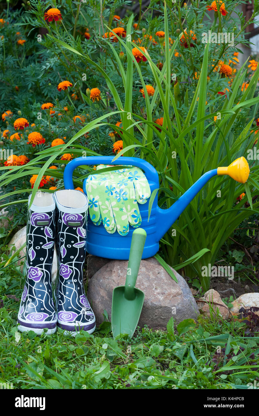 Herramientas de jardinería. botas de caucho, azul regadera, guantes y pala  en fiower jardín Fotografía de stock - Alamy