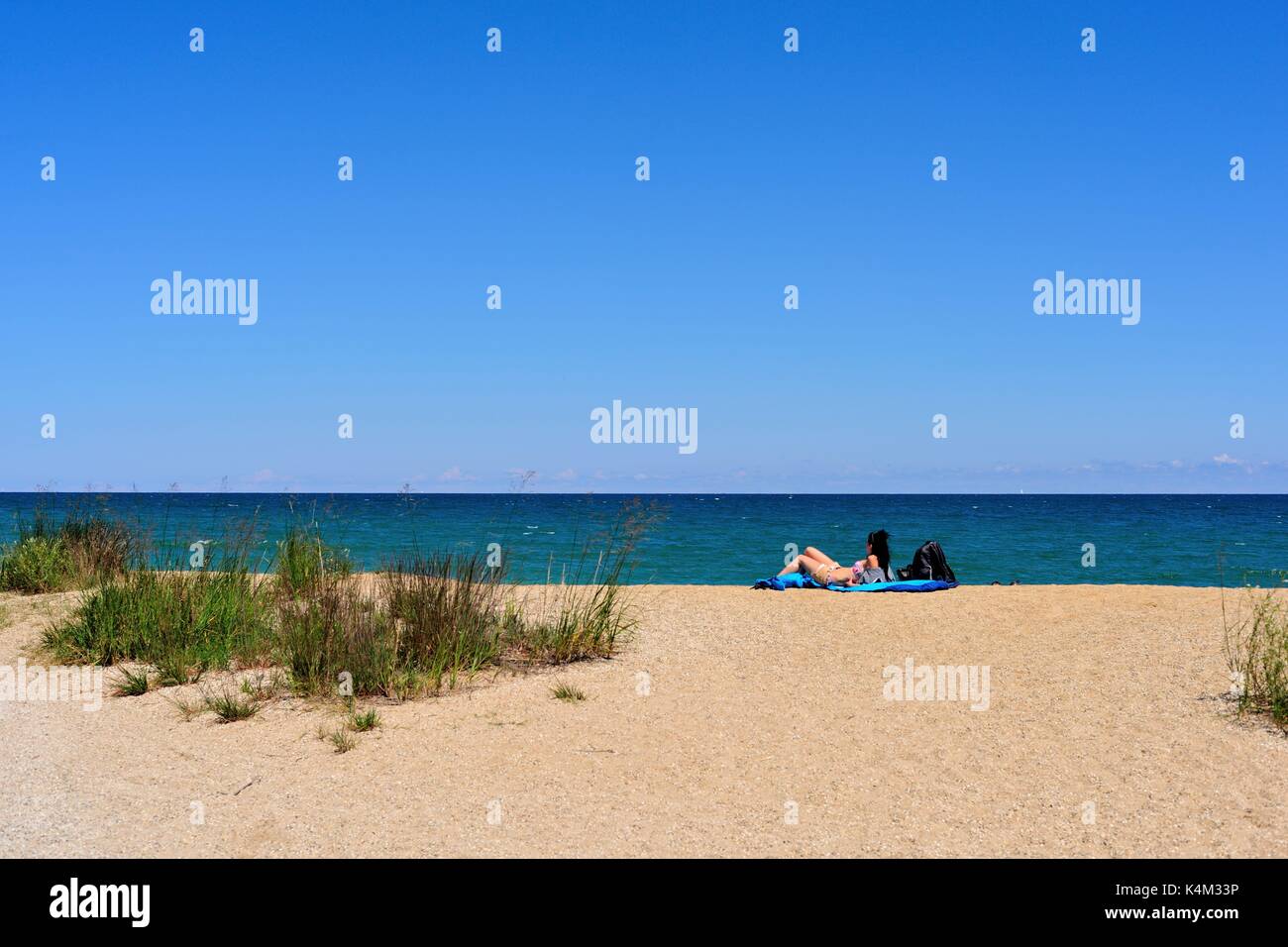 Una mujer solitaria se relaja en la arena entre las dunas en Illinois Beach State Park en Zion, Illinois, en la orilla del Lago Michigan. Ee.Uu.. Foto de stock