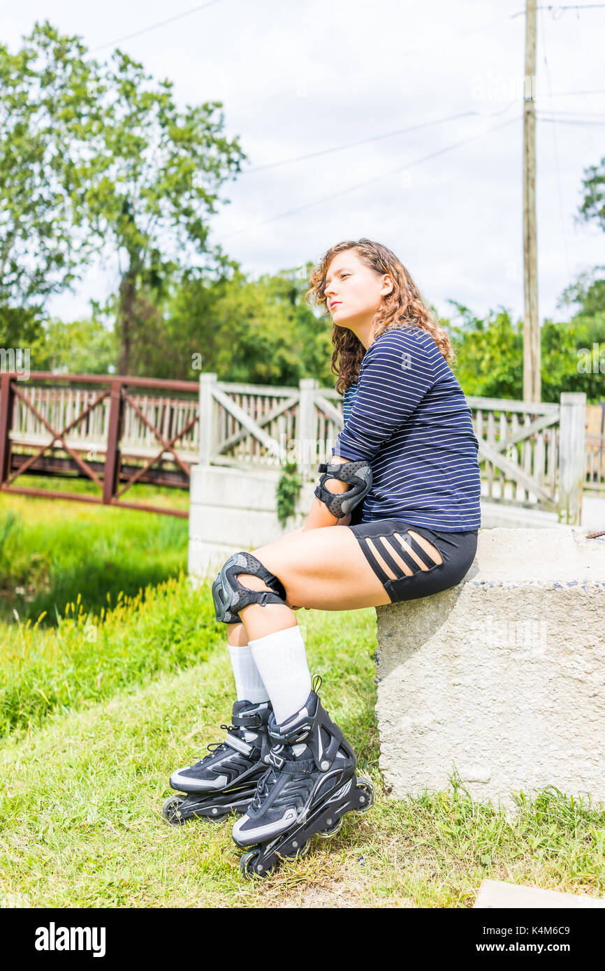 Mujer joven sentada con patines en línea fuera del parque en verano  descansando con rodilleras y coderas Fotografía de stock - Alamy