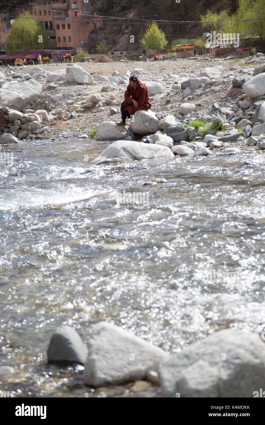 Hombre bereber se relaja por el río durante el zoco de Setti Fatma, valle de Ourika, las montañas del Atlas, Marruecos Foto de stock