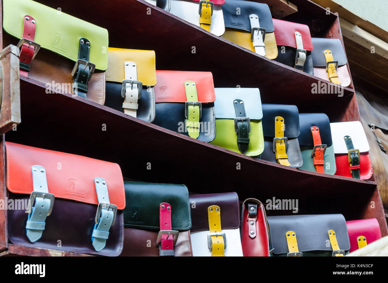 Bolsas de colores en la pantalla para la venta en un estante en un cuero de buen fabricante y minorista en el mercado de Camden, Londres. Foto de stock