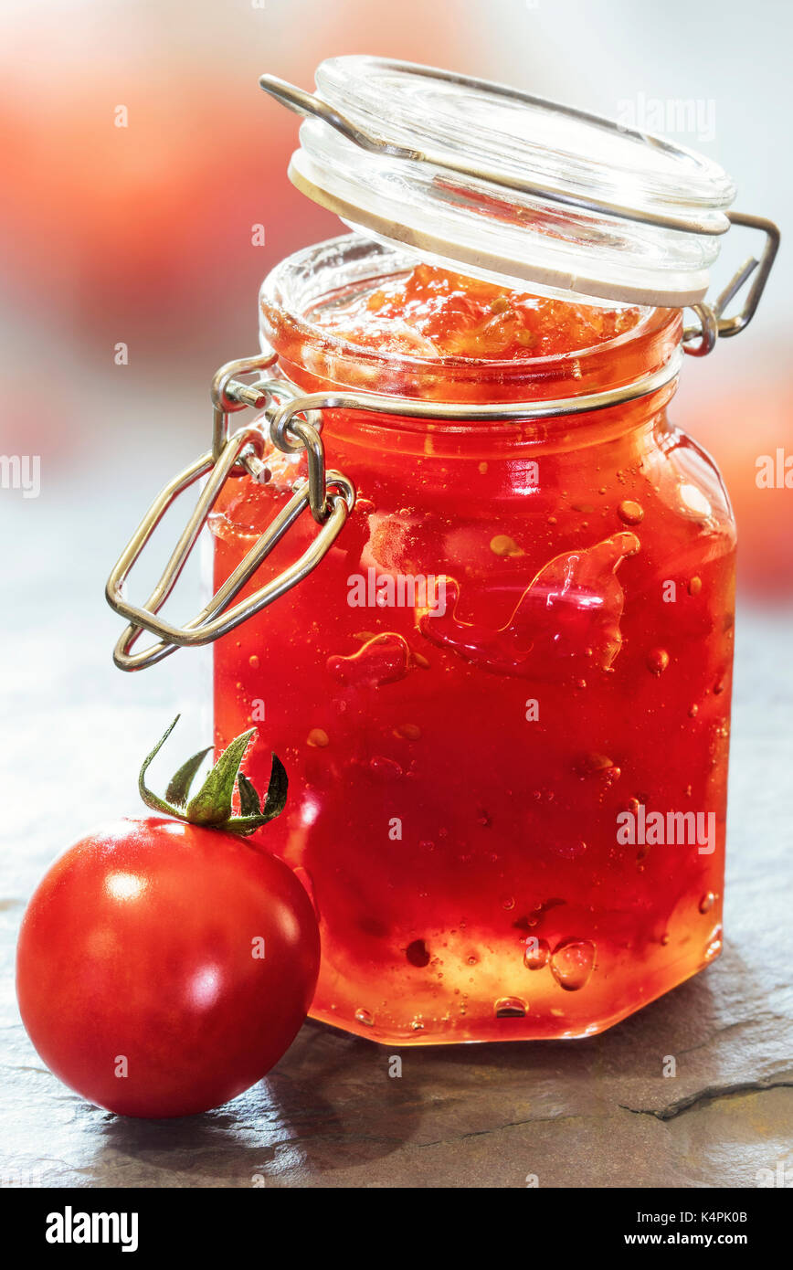 Mermelada de tomate en un frasco de vidrio sobre una mesa de pizarra Foto de stock