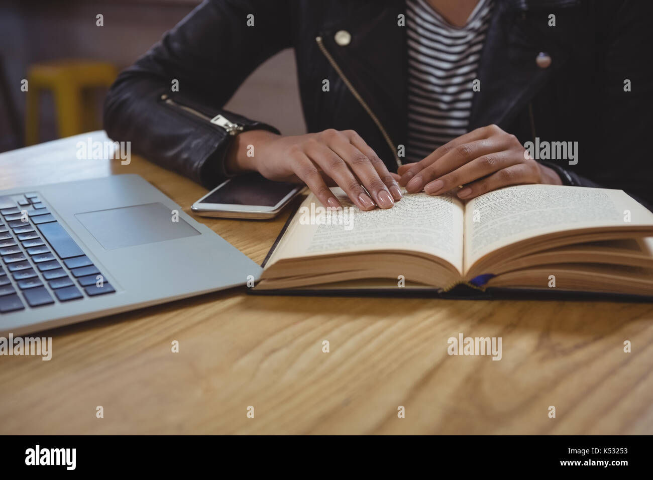 La sección central de la mujer con el libro en la mesa de madera en el cafe Foto de stock