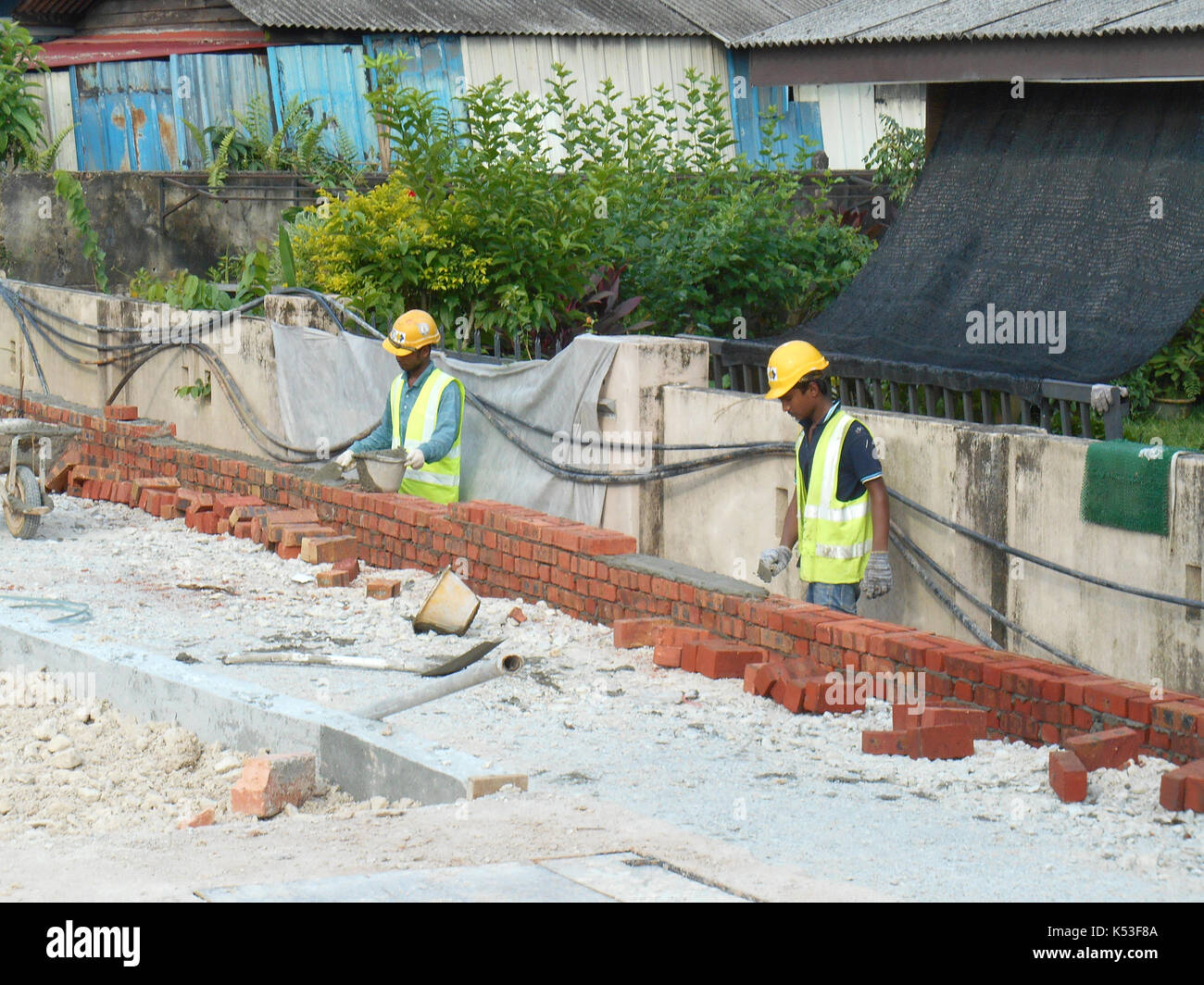 Selangor, Malasia - enero 15, 2017: albañil sentar los ladrillos y bloques apilados juntos con mortero de cemento para formar las paredes de la construcción Foto de stock