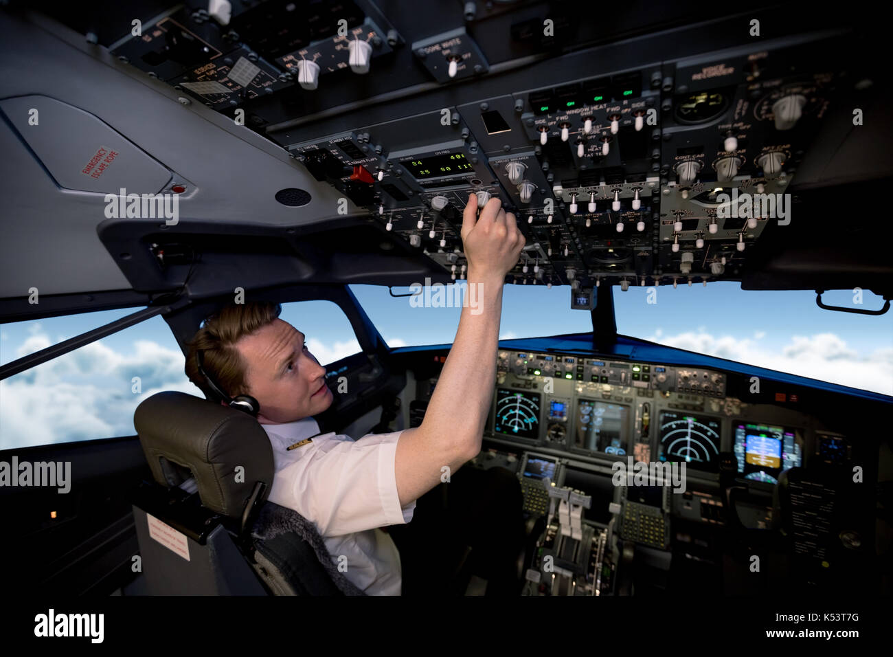 Apuesto joven piloto cambiar los controles en la cabina del avión Foto de stock