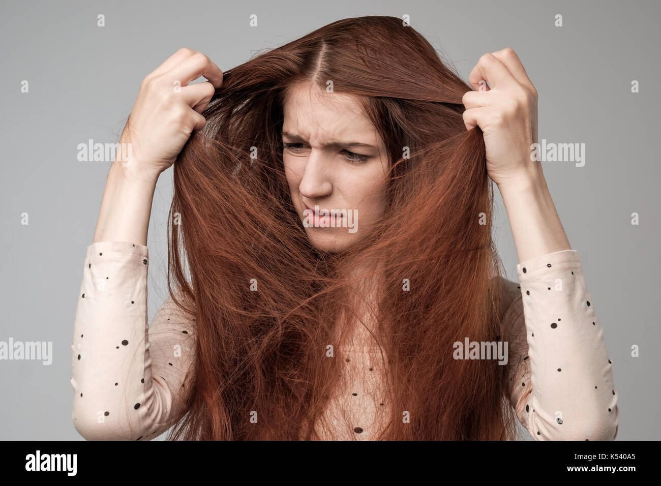 Bonita mujer caucásica tratando de peinar el cabello. Foto de stock