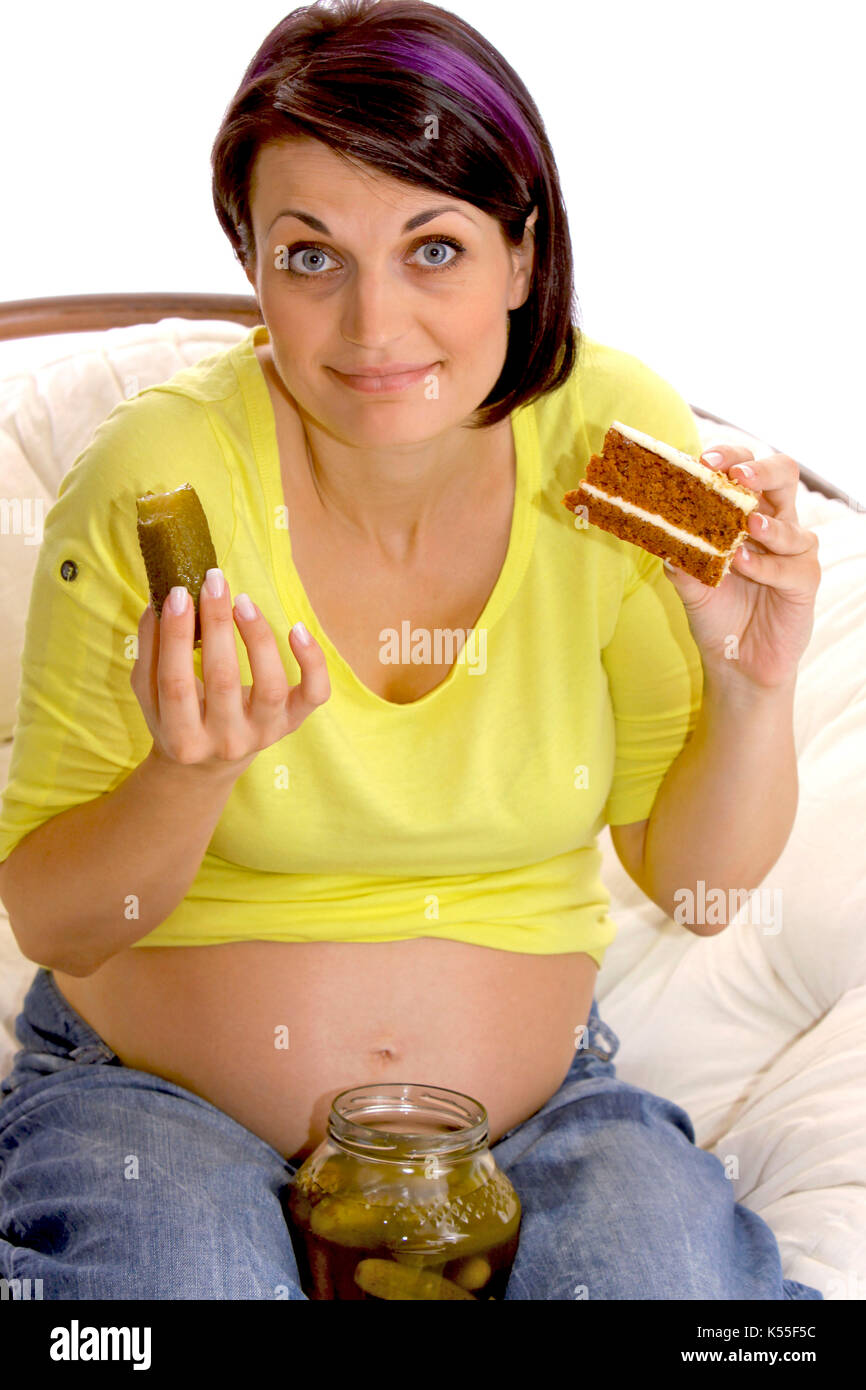 Mujer embarazada comer un trozo de pastel dulce y agrio pickle juntos Foto de stock