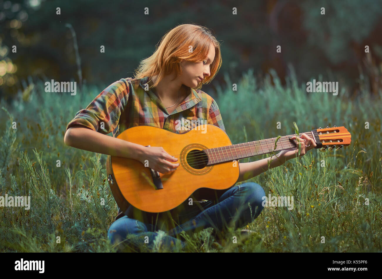 Bonito Joven Mujer Caucasica Plaid En Camiseta Y Pantalones De Mezclilla Esta Tocando En Una Guitarra Acustica En Una Pradera De Verano De Fondo Fotografia De Stock Alamy