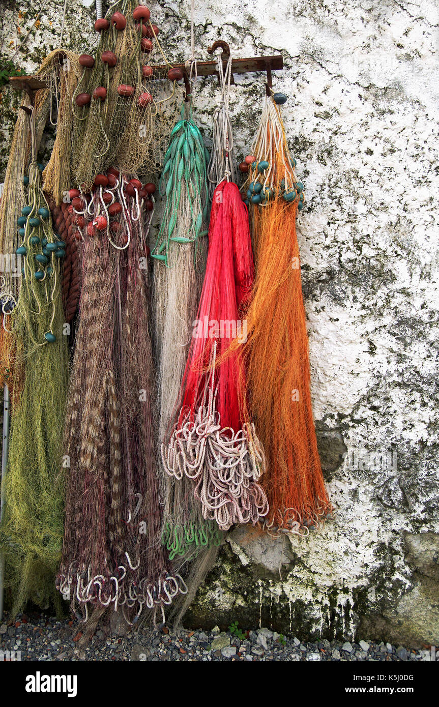 Algunas redes de pesca de colores colocadas en una pared blanca exterior Foto de stock