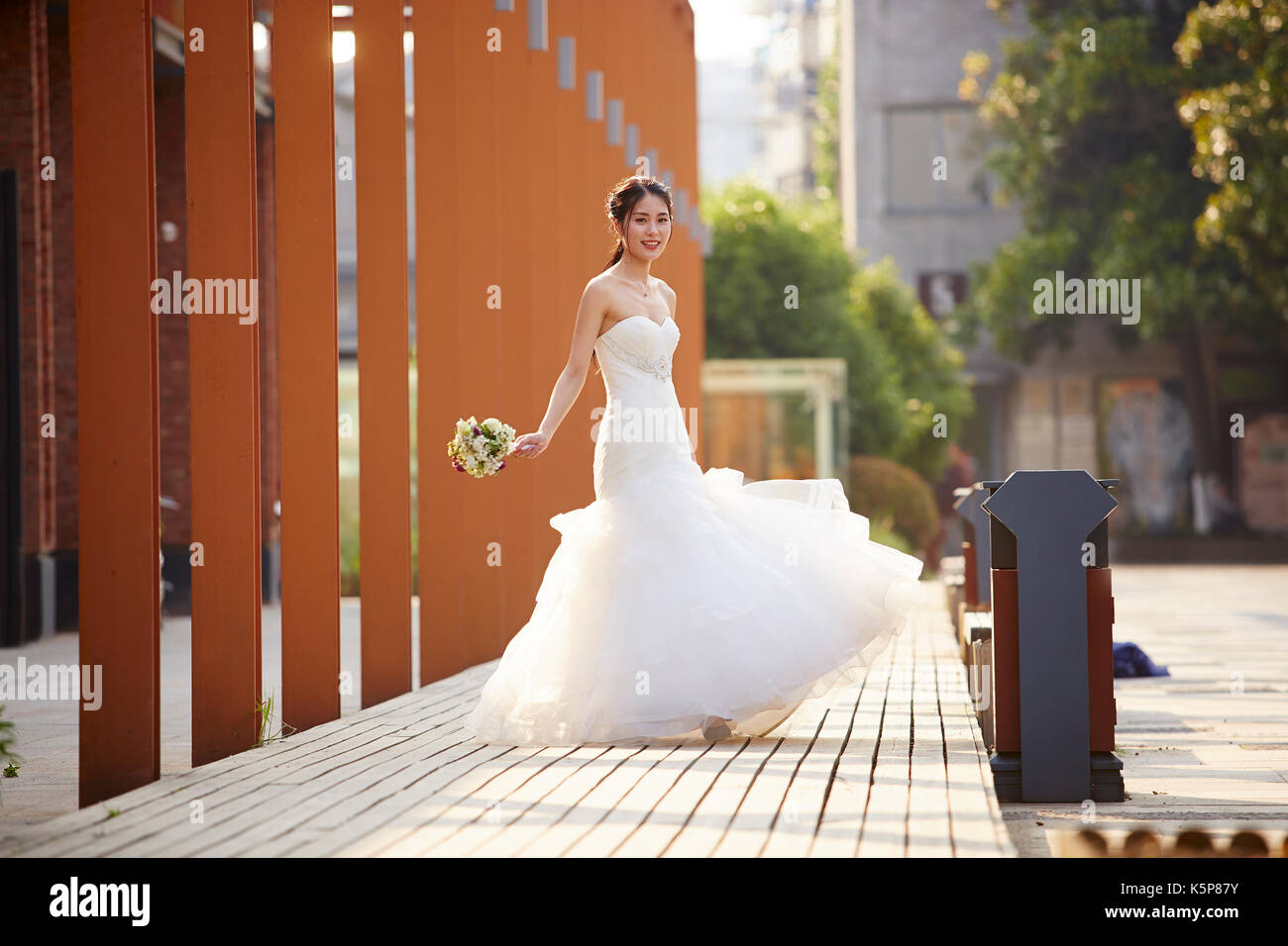 Outdoor retrato de joven y bella asiática novia con ramo en la mano. Foto de stock