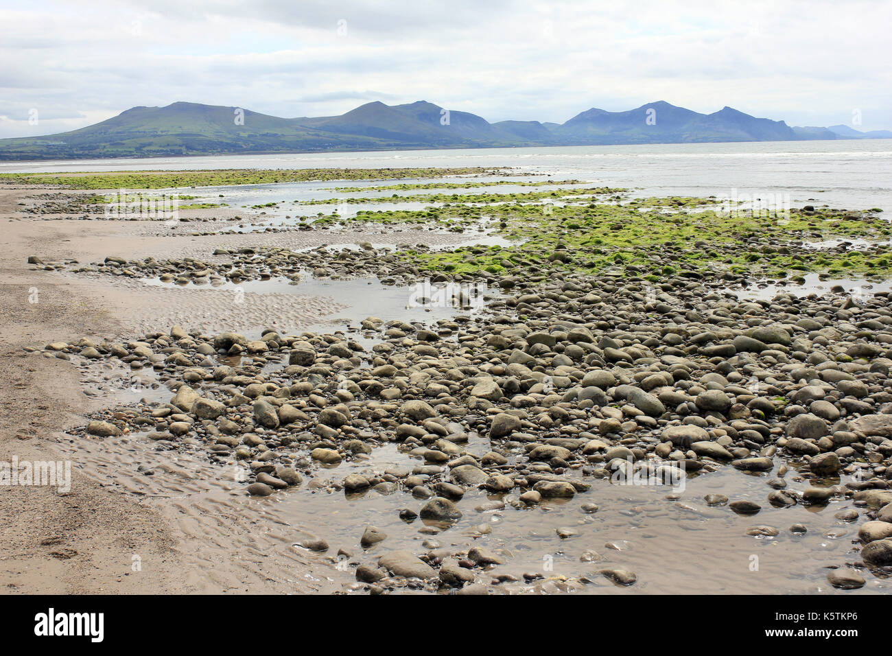 Playa de guijarros de Dinas Dinelle con la península de Llyn en segundo plano. Foto de stock