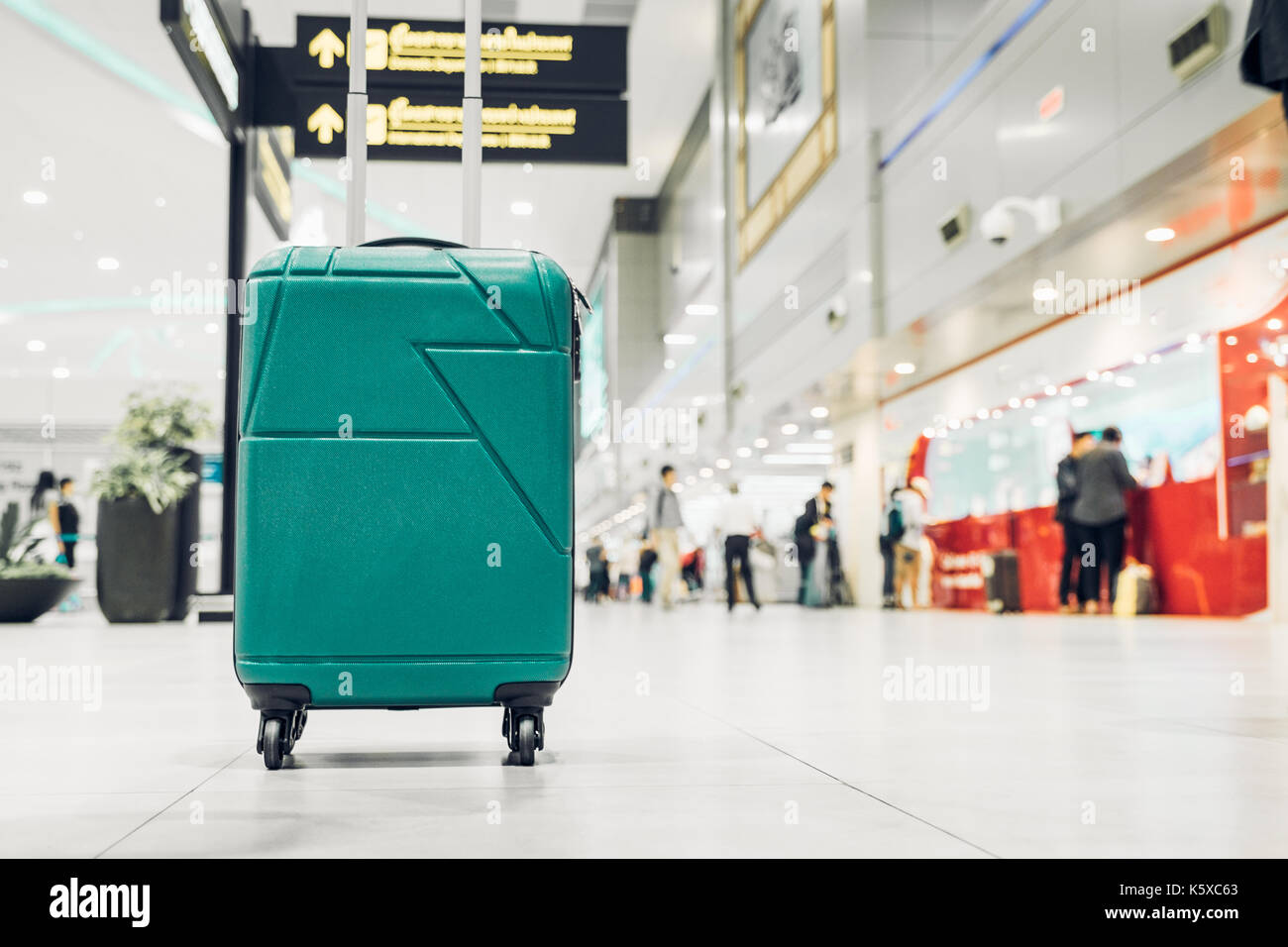Las maletas en la terminal de salidas del aeropuerto de viajero con gente caminando en el fondo, el concepto de vacaciones vacaciones, viaje de negocios,el enfoque selectivo en maleta Foto de stock