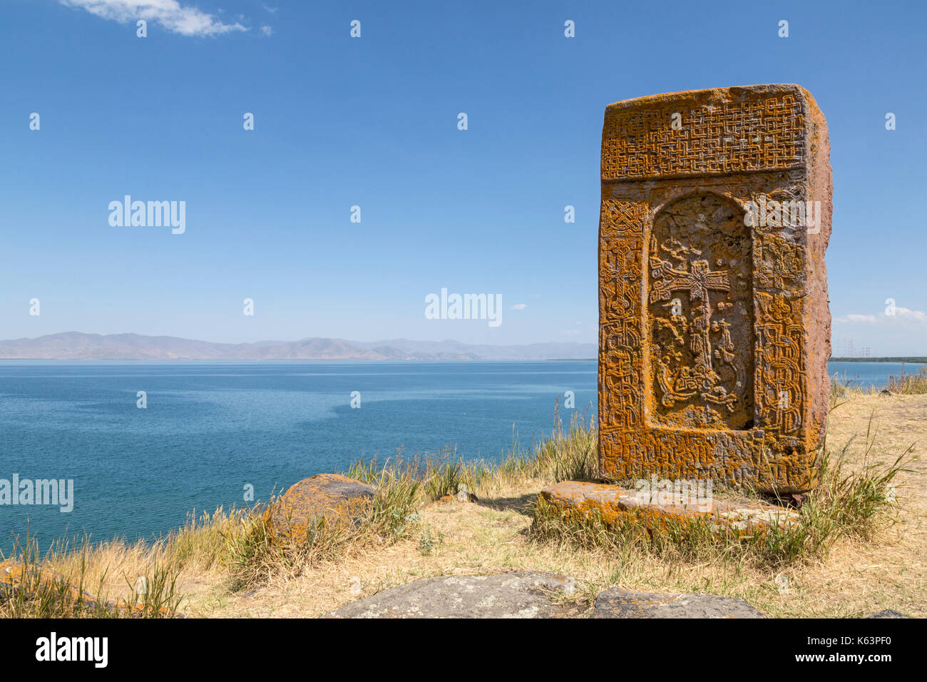 Cruz de piedra tradicional llamado Khatchkhar con vistas al Lago Sevan en Armenia. Foto de stock