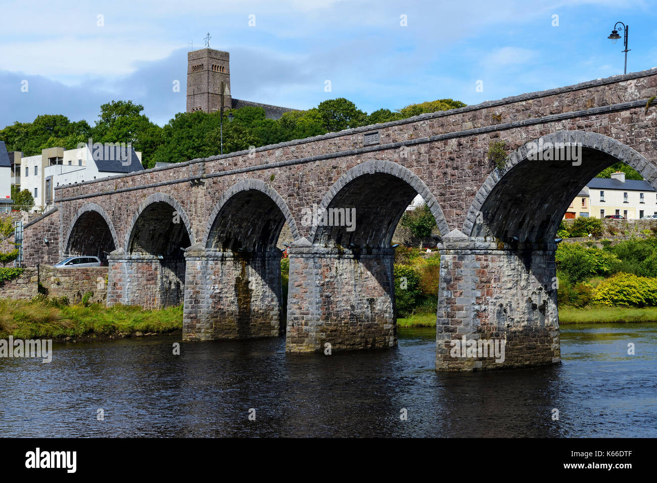 Siete Arch puente que cruza el río Newport con St Patrick's Church de fondo, Newport, en el condado de Mayo, República de Irlanda Foto de stock