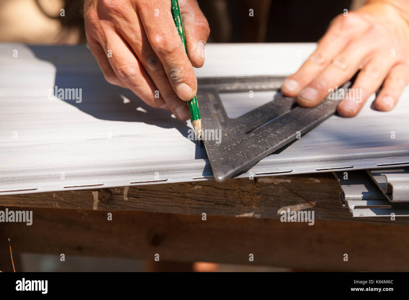 Un trabajador de la construcción de marca vinyl siding utilizando un lápiz y un triángulo o cuadrado en Ontario, Canadá. Foto de stock