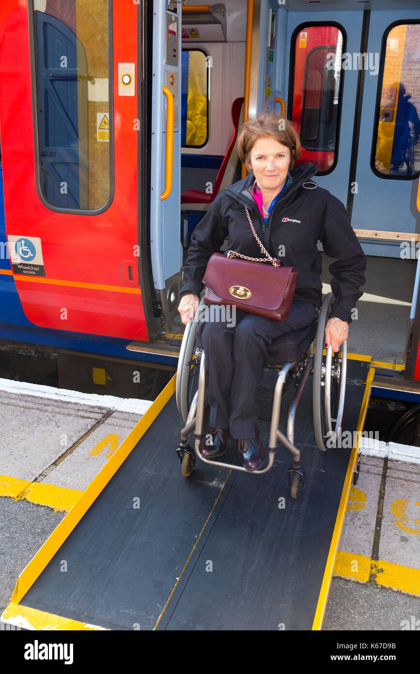 Usuario de silla de ruedas / persona en silla de ruedas partiendo / Salir / descienda del tren transporte sobre una plataforma con una rampa siempre en la estación. Foto de stock