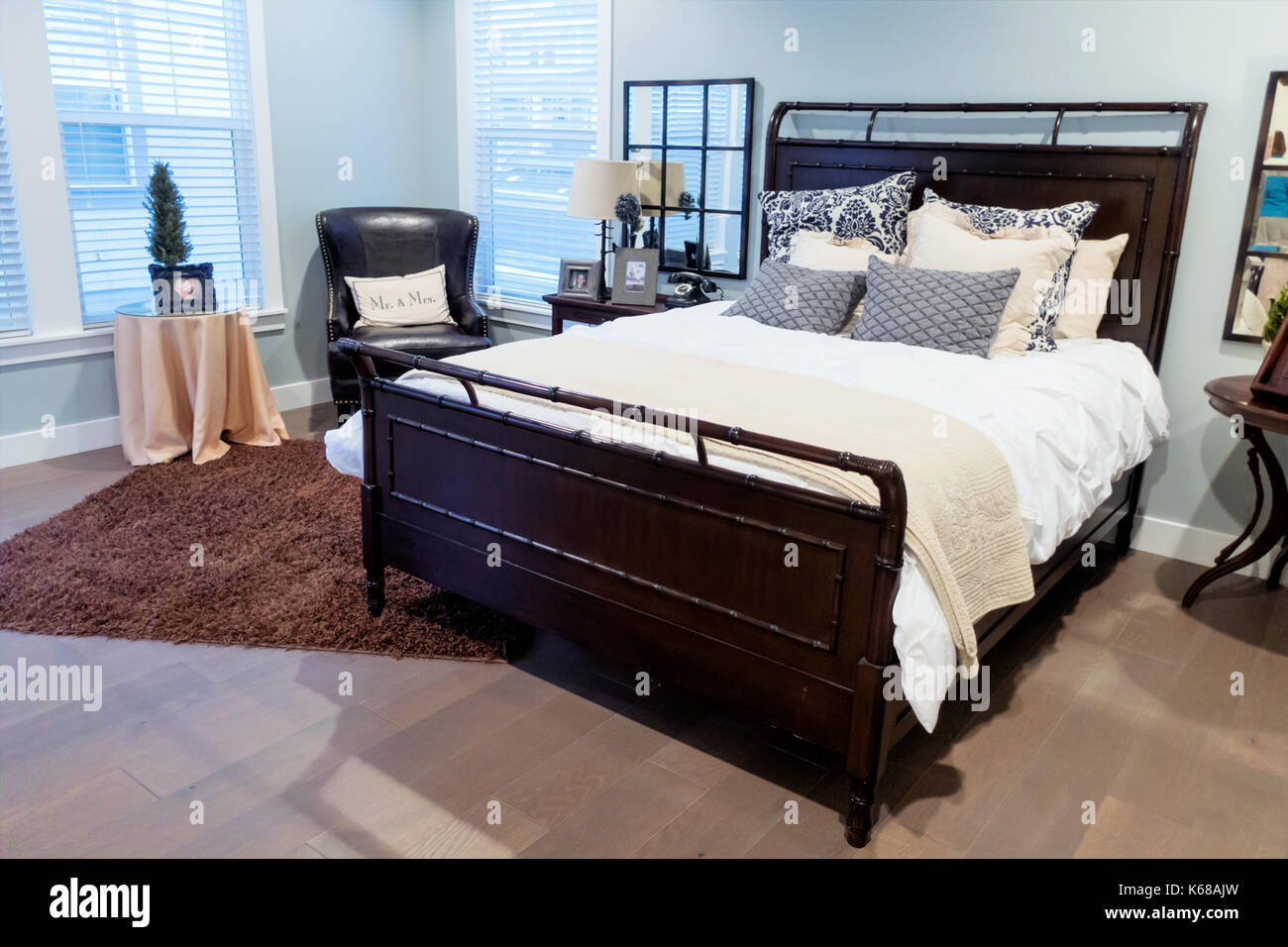 Un acogedor dormitorio principal con una cama grande, noche de stands, un aparador y un suave shag rug. Foto de stock