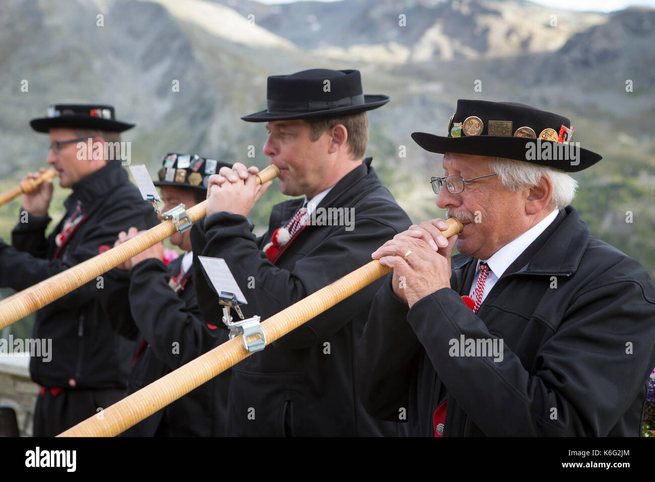 Cuatro lugareños jugando alphorn vestidos tradicionalmente, Zermatt, Valais, Suiza Foto de stock