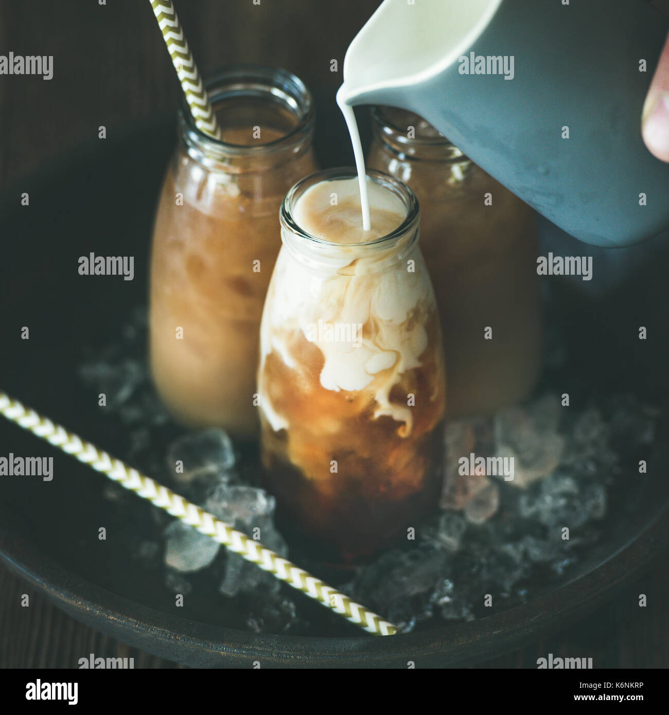 Bebida refrescante de verano. frío thai iced tea en botellas de vidrio con  leche colada de blanco jarra sobre placa sobre fondo de madera oscura, el  enfoque selectivo, s Fotografía de stock -