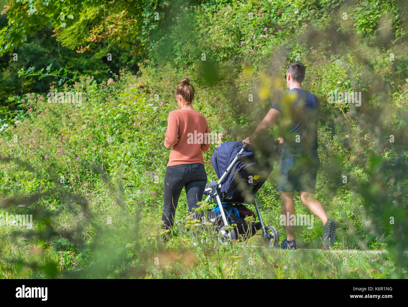 Pareja con un niño en un cochecito con un campo caminar en otoño en el Reino Unido. Foto de stock